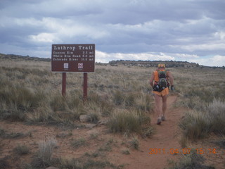 263 7j7. Canyonlands Lathrop hike/run - Adam running with sign