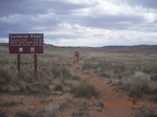 266 7j7. Canyonlands Lathrop hike/run - Adam running with sign