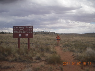 267 7j7. Canyonlands Lathrop hike/run - Adam running with sign
