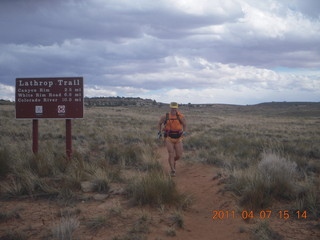 268 7j7. Canyonlands Lathrop hike/run - Adam running with sign