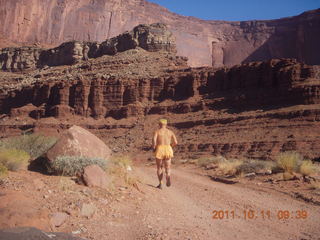 75 7qb. Canyonlands National Park - Lathrop trail hike - Adam running - back (tripod)