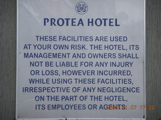 113 8f7. Uganda - Entebbe - Protea Hotel - sign (too many lawyers)