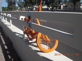 orange bike chained to a road fence