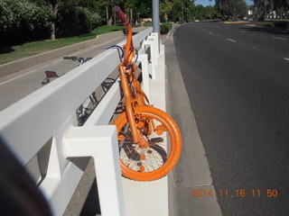 orange bike chained to a road fence